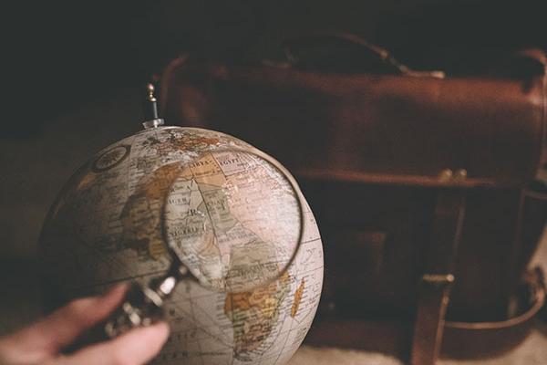 A photo of a magnifying glass, globe, and bag