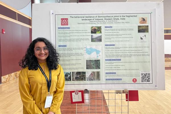 image of Nagarathna Balakrishna presenting her poster. Nagarathna is a short woman wearing a yellow blouse with long black hair, she is also wearing lanyard and glasses