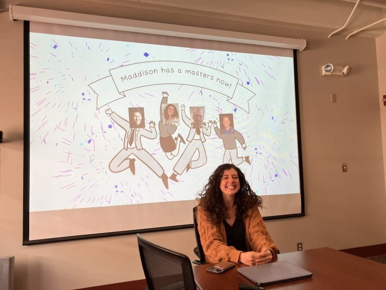 Maddison Elliot in front of projector celebrating earning her masters degree