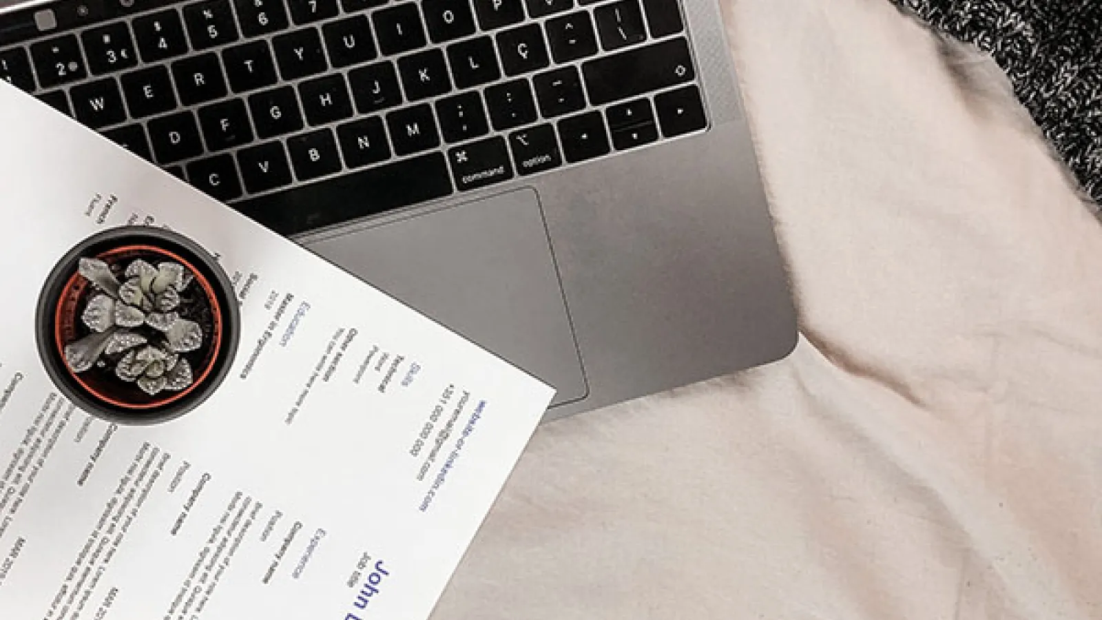 Laptop computer is open with paper resume on top of keyboard
