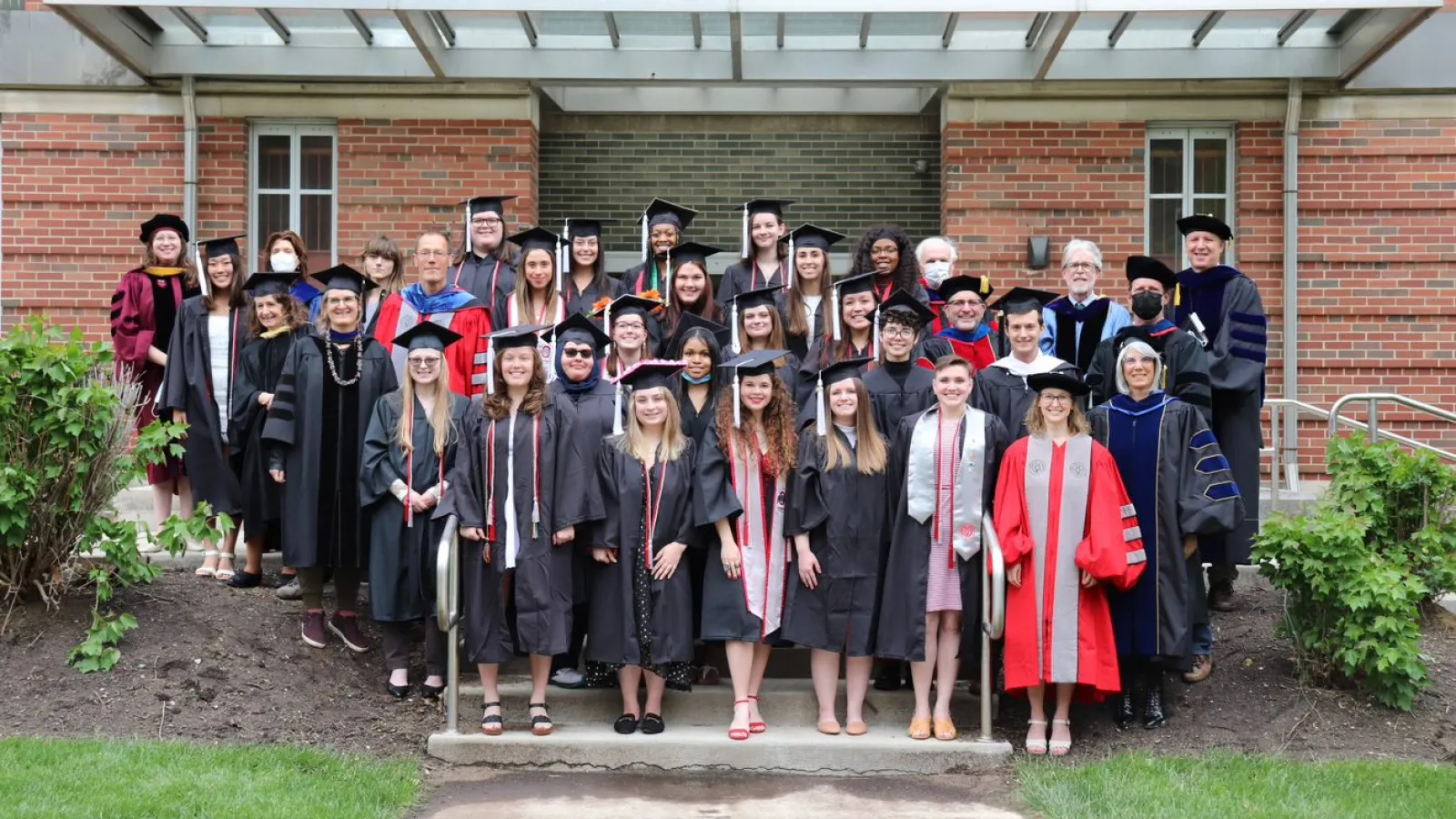 Graduating students standing together in front of a brick building