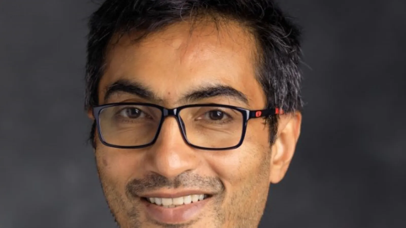 Smiling dark haired man with glasses