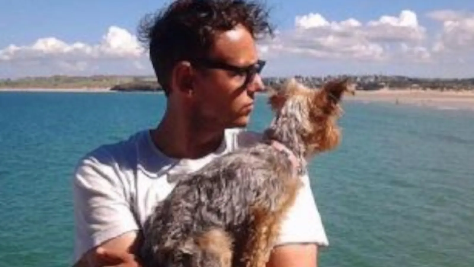 Dark Haired white man holding his dog