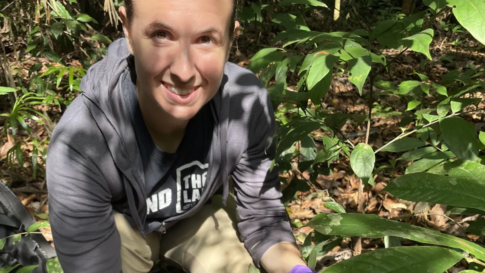 woman crouching in the brush holding a spoon