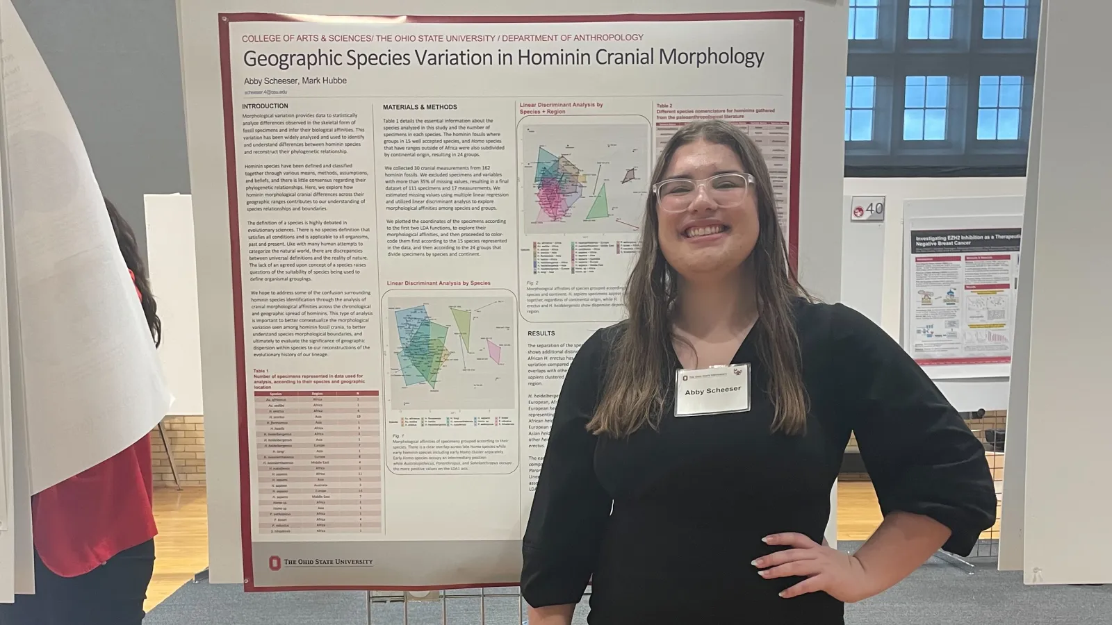 Smiling woman with long hair presenting a research poster.