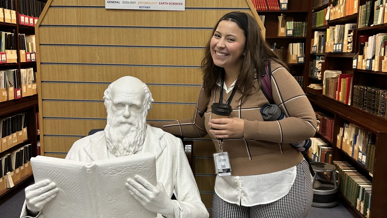 Woman posing in front of a white statue of Charles Darwin.