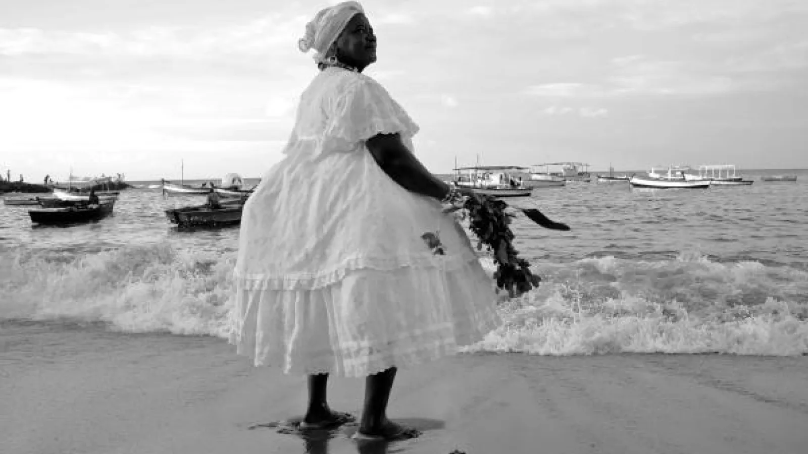 A baiana woman on the beach with boats in the background