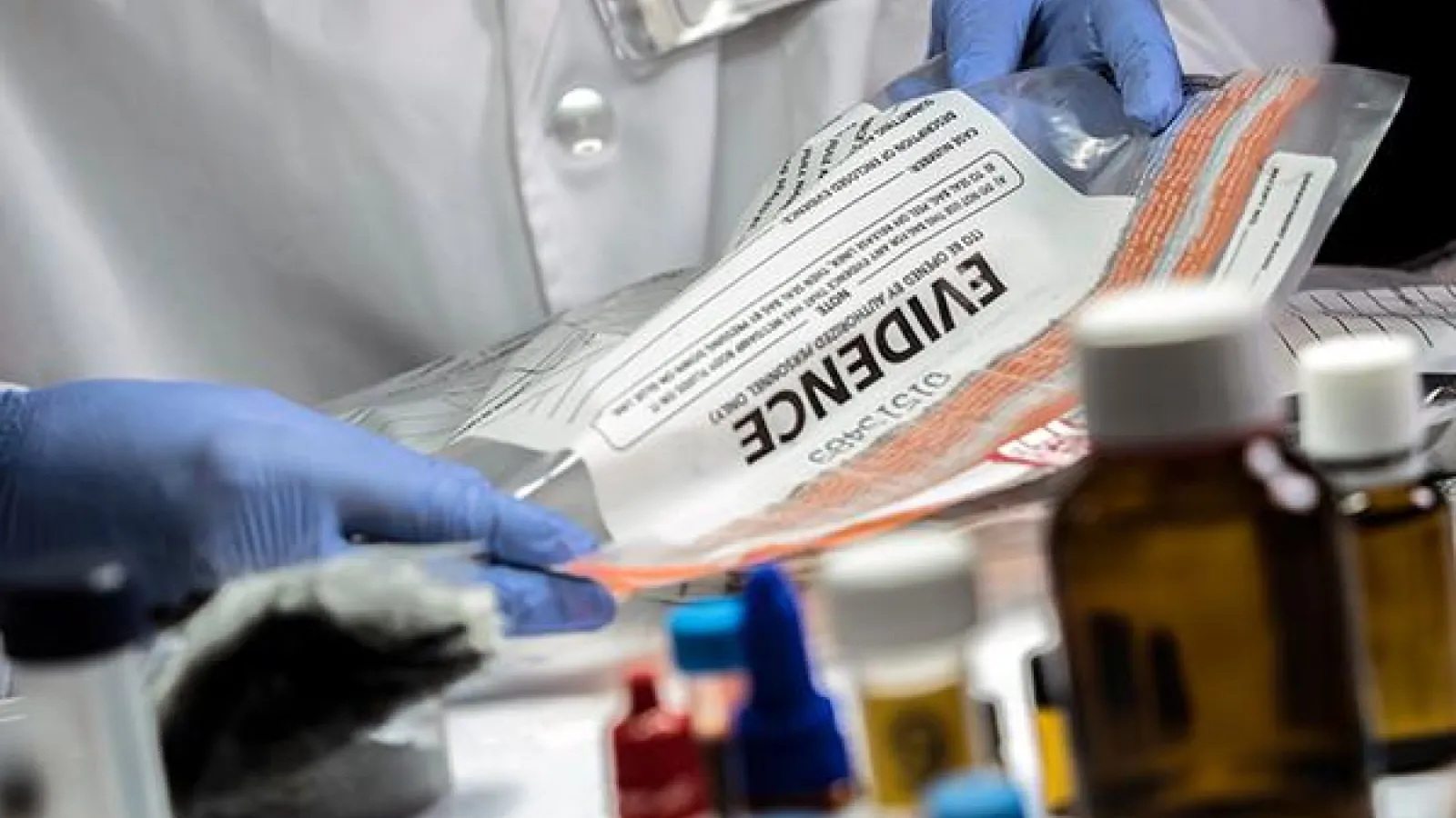 gloved hands holding a bag labeled "evidence"