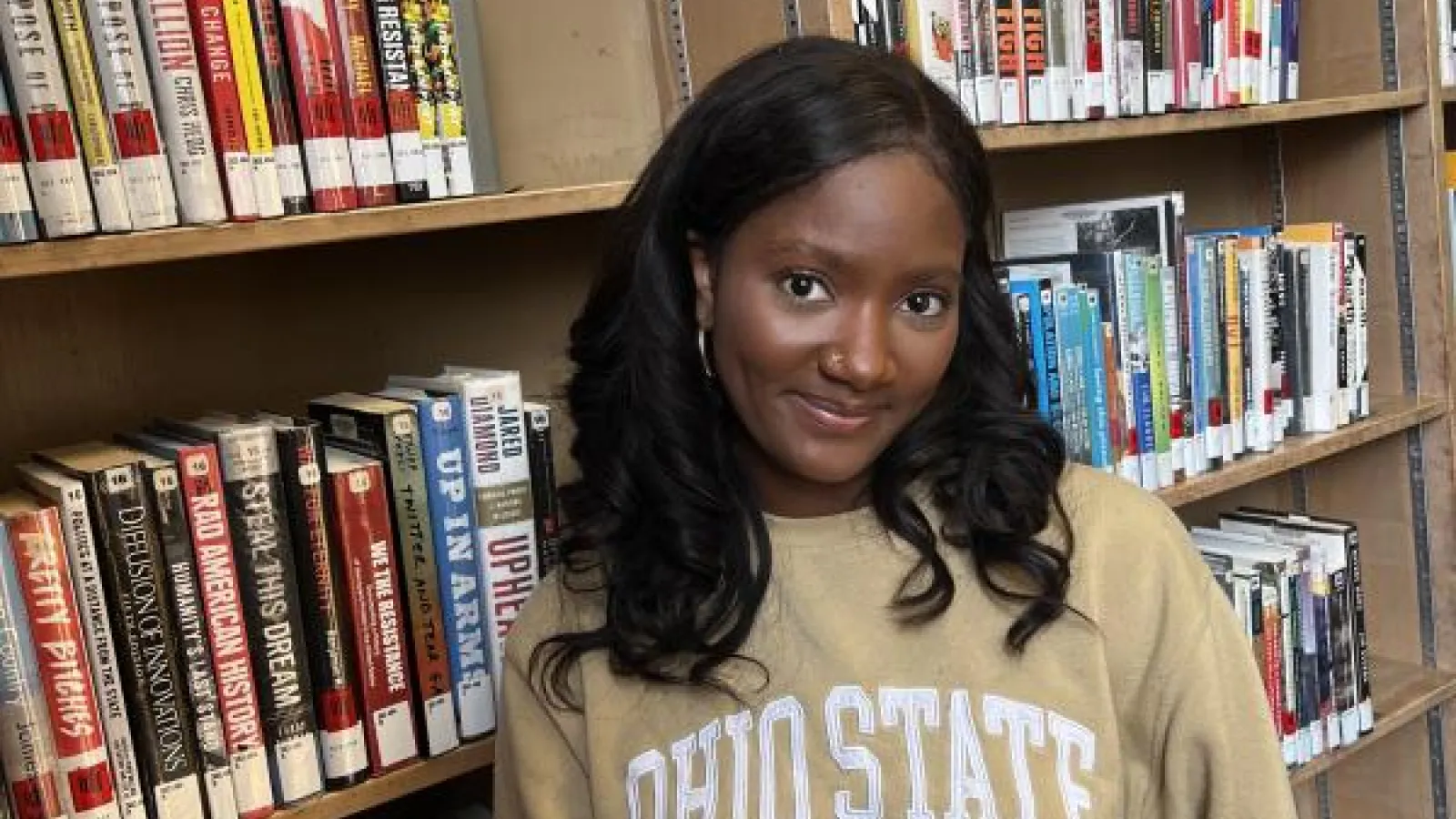 Smiling black woman standing in front of book shelves