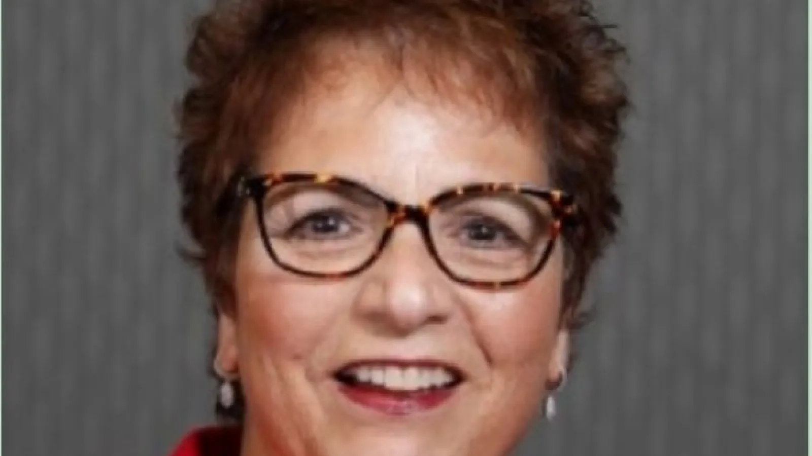 Smiling woman with curly brown hair and glasses