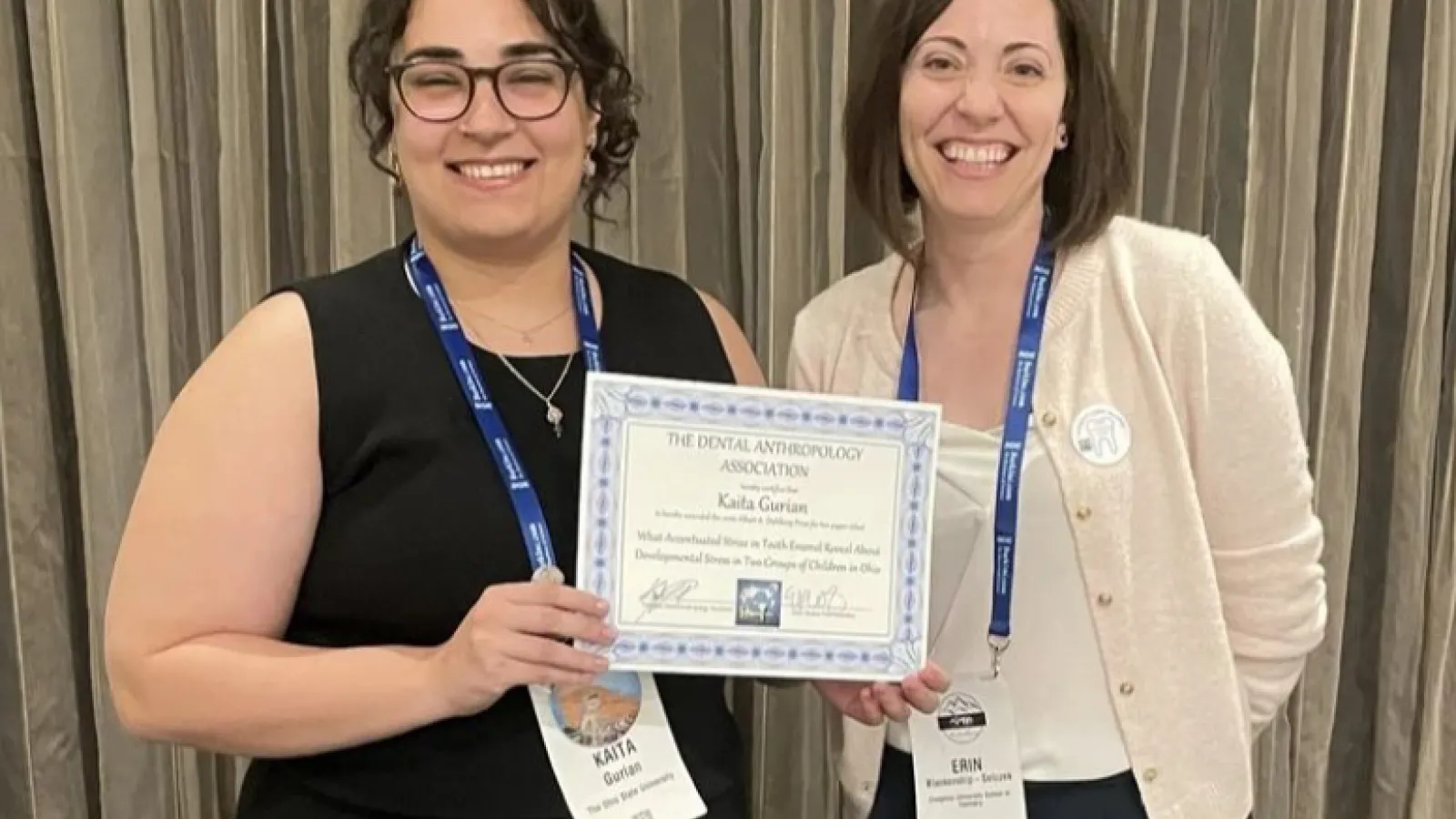 Two women standing side by side as an award is presented