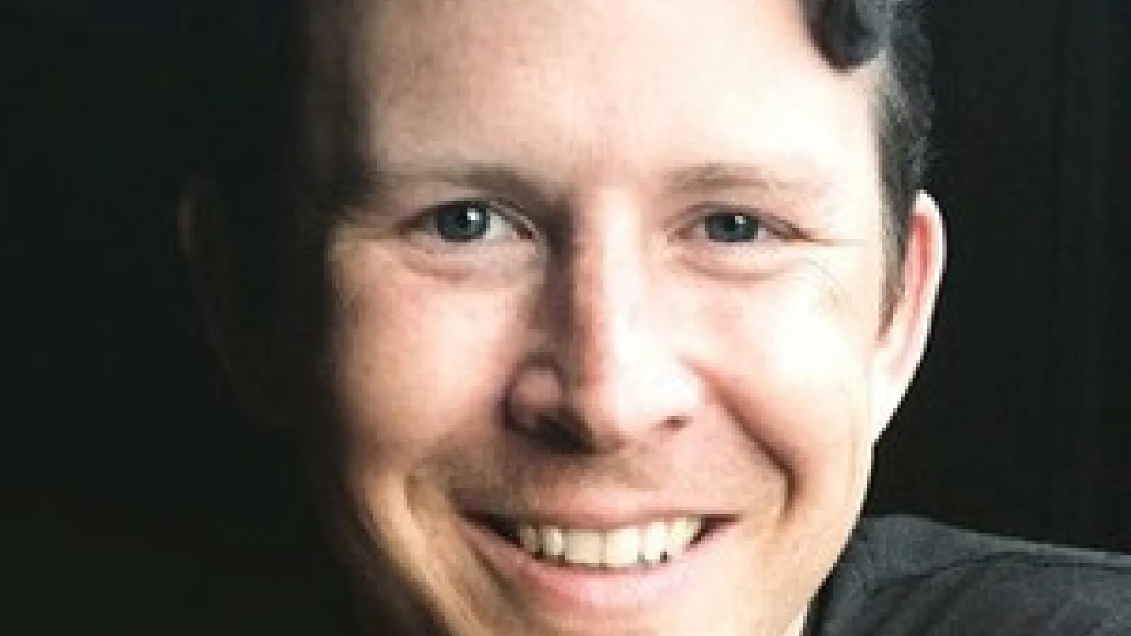 Dark haired man smiling into the camera