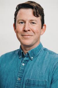 White man with dark red hair smiling at camera