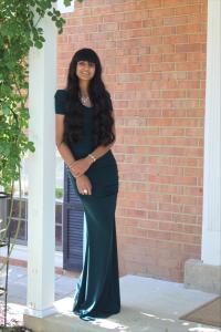 Woman with long dark hair standing by a white pillar