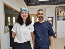 Woman in blue head scarf standing next to a man in dark blue scrubs