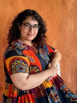 Dark haired woman with glasses in a colorful dress