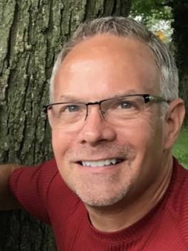Smiling grey haired man in glasses and a red shirt