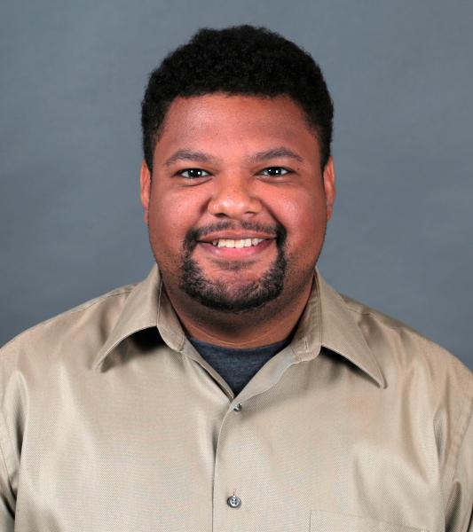 Smiling dark skinned man with short dark hair and beard