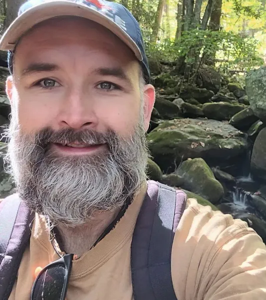 Smiling white man with grey beard and a ball cap