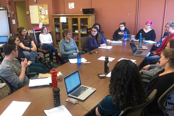 Grads, undergrads, and faculty sit around a table to discuss applying to graduate school