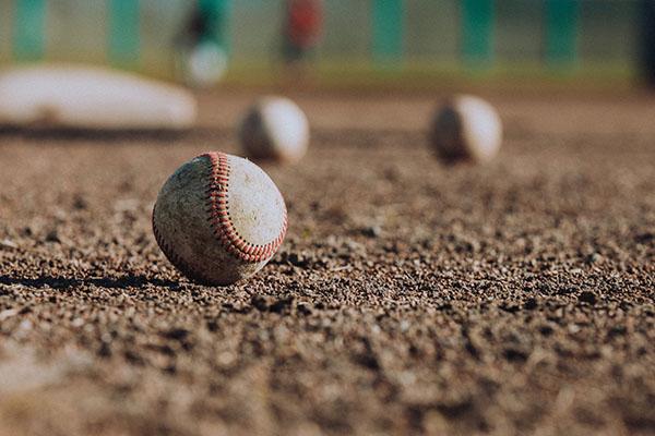 A photo of baseballs on a baseball field with a base in the background