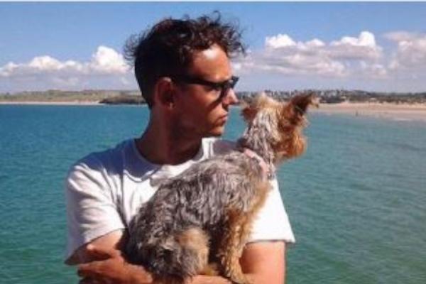 Dark Haired white man holding his dog