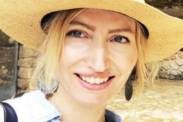 Blond woman wearing a full brimmed hat, a black necklace and collared shirt