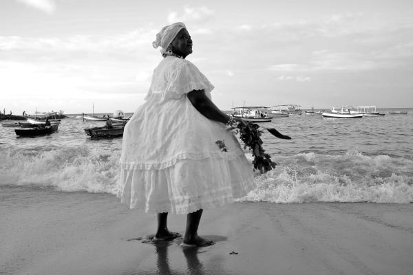 A baiana woman on the beach with boats in the background