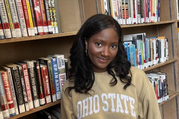 Smiling black woman standing in front of book shelves