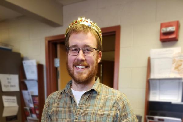 Dr. Comstock wears traditional crown and holds baby from King Cake