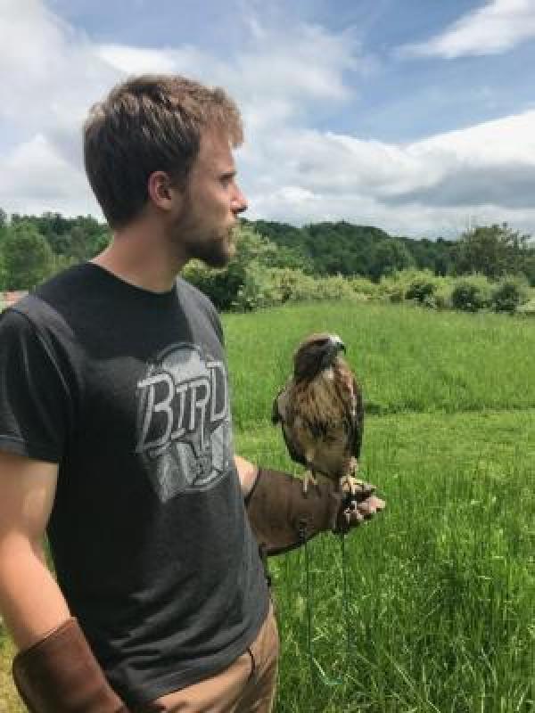 White blond haired man holding a hawk on his hand