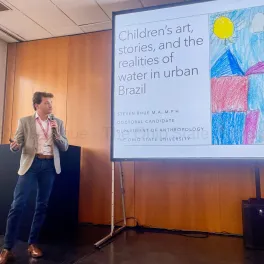 White man in suit presenting his research