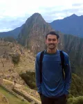 Dark haired man standing in front of mountains